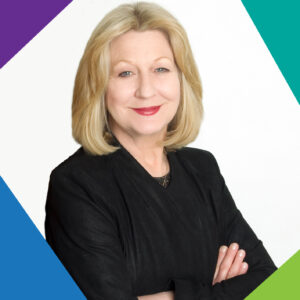 Clare Collins, Chair Advocacy Australia is a blonde woman with shoulder length hair wearing a black suit jacket with her arms folded.